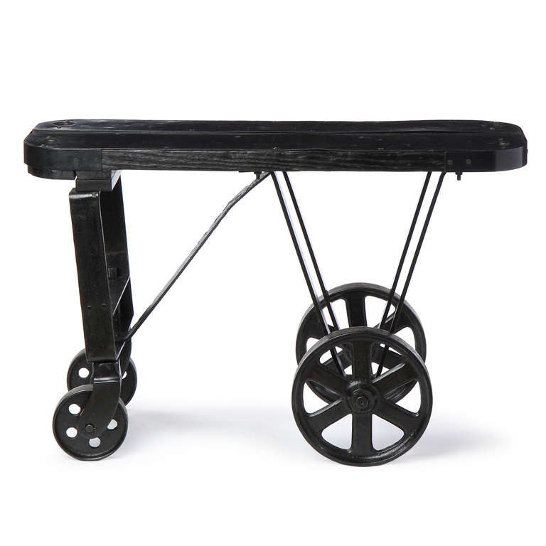 An unusual and interesting ebonized oak and patinated steel topped industrial cart with large cast iron wheels.