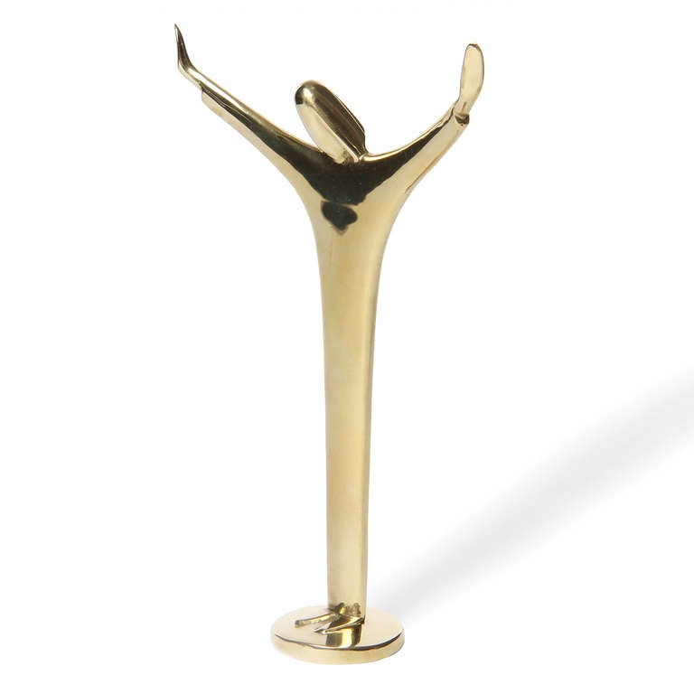 A modernist brass sculpture of Jesus Christ with outstretched arms.
