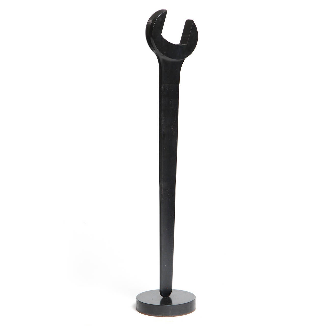 A dramatically oversized patinated forged steel wrench beautifully mounted on a circular base.