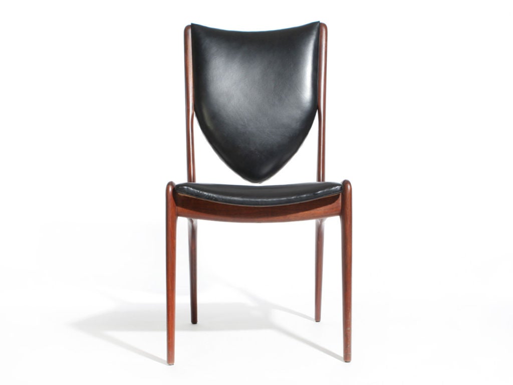 A walnut dining/side chair with a floating seat and shield-form backrest retaining the original fabric.
