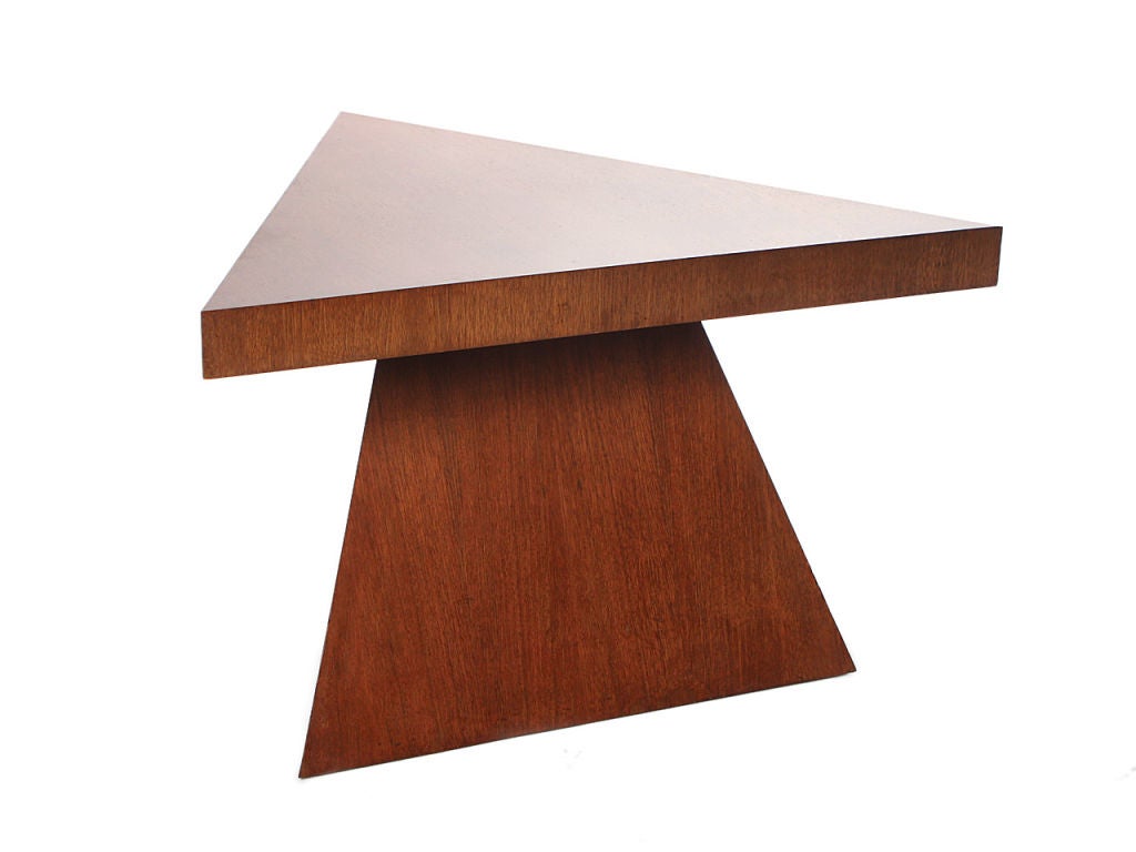 A mahogany triangular low table on a pyramid base.