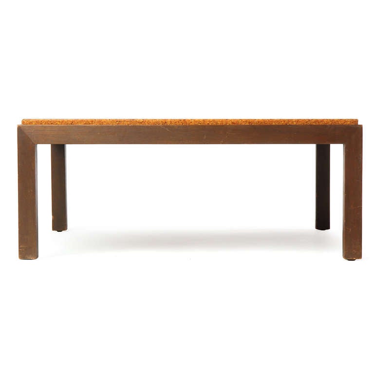 Ein einfacher und eleganter quadratischer niedriger Tisch mit einer erhöhten Korkplatte auf einem Mahagonisockel.
 