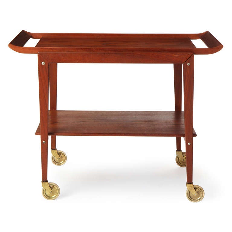 An architectural Scandinavian Modern teak cart with a removable tray and single shelf on brass castors. Made in Denmark, circa 1960s.