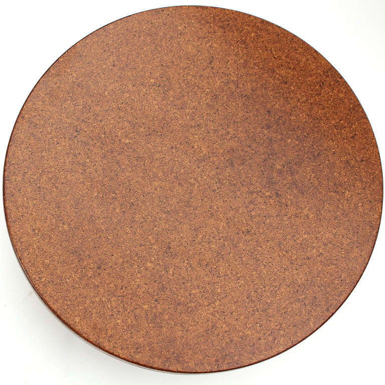 An uncommon circular cocktail or low table having a veneered cork top floating on three wide splayed mahogany legs.