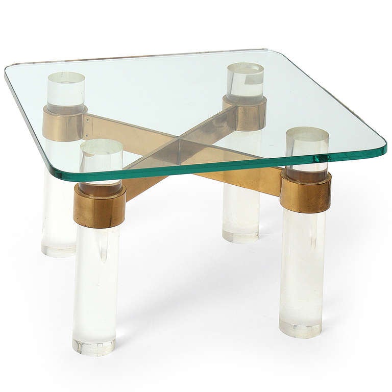 A striking end or occasional table comprised of a thick glass top resting on four substantial lucite columns connected with a wide solid brass stretcher.