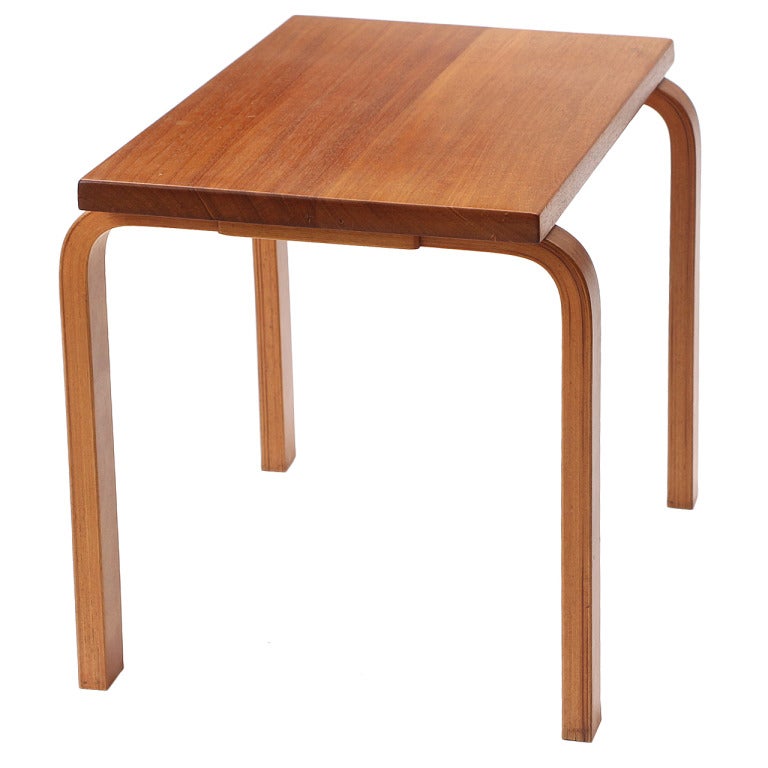 A table having a rectangular top in solid teak floating on laminated bent Finnish birch legs.