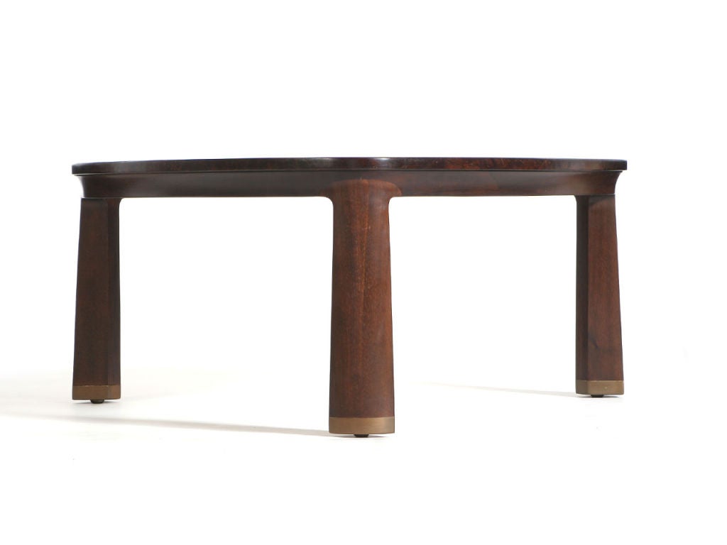 A triangular low table with a burled Carpathian elm top, mahogany base and brass tipped legs.