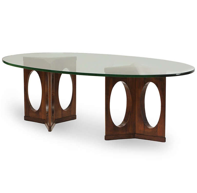 A custom-designed dining or conference table with two wood triangulated open bases supporting a long oval glass top.