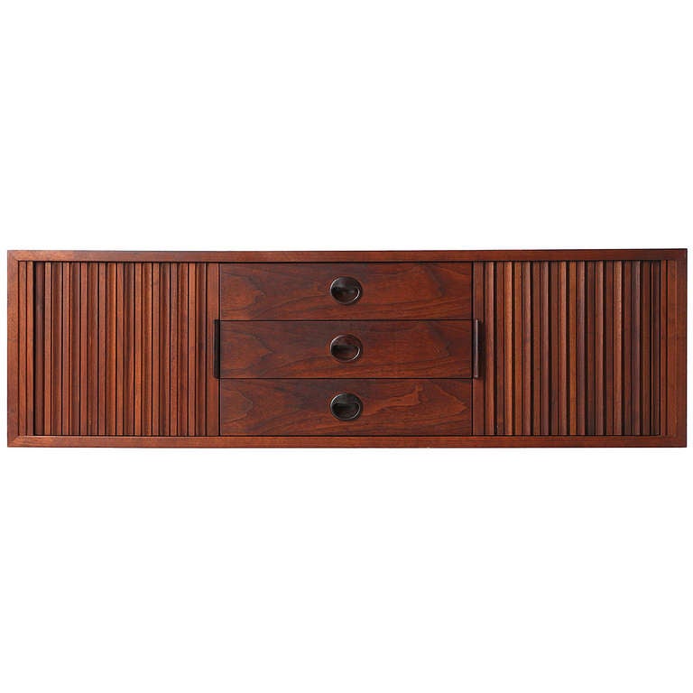 A set of four wall-mounted modular cabinets which can be arranged together or separately. The set is made of walnut with recessed rosewood pulls; the tall cabinet can be locked.