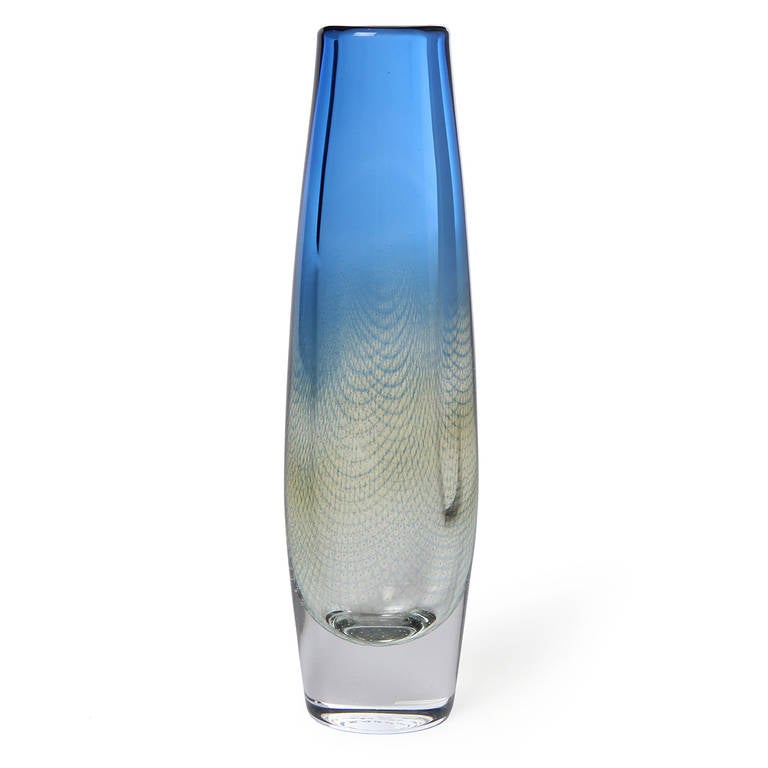 A uniquely designed tapering glass vase, of the Kraka line, in a blue to yellow fade with a fishnet pattern and air bubbles trapped in the cross sections of the net.