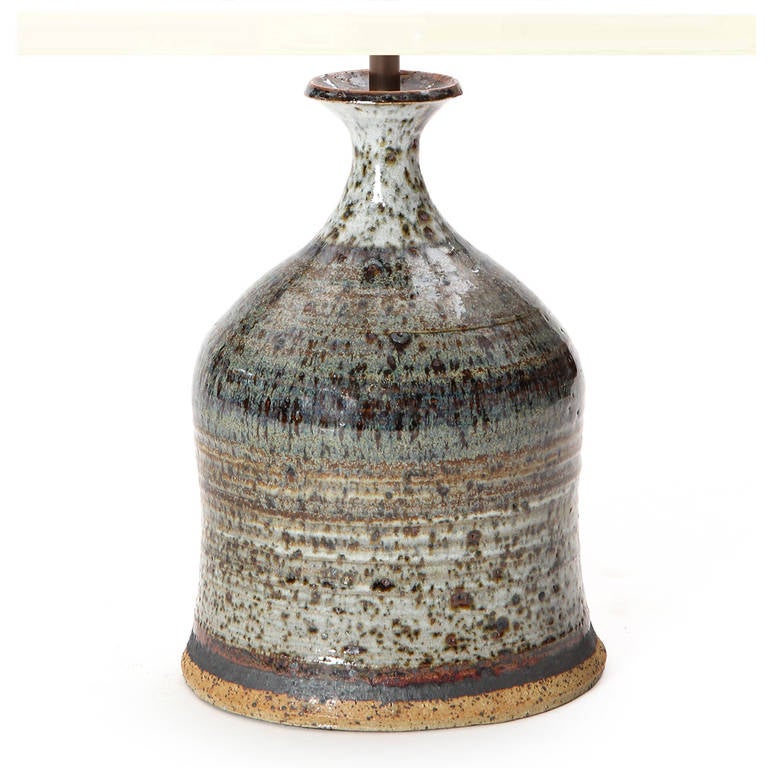 A fine ceramic table lamp with a pinched neck form in a grey and earth tone speckled glaze.
