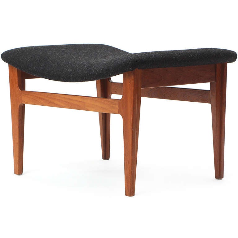 A simple and elegant ottoman or stool crafted of solid teak and upholstered seat in charcoal grey wool.