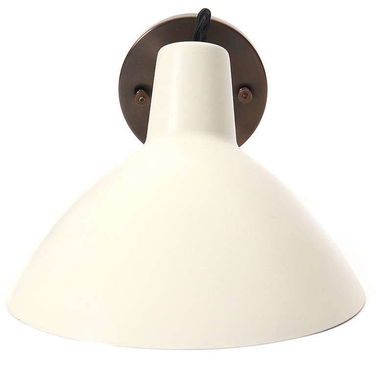 A wall light or sconce having an asymmetrical adjustable shade in painted white finish with brass stem and bracket.