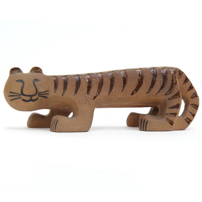 A whimsical earthen ware ceramic tiger with brown glazed stripes.