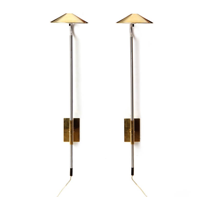 A pair of adjusting wall-mounted sconces in brass and chrome having swiveling shades. These sconces may also be height adjusted.