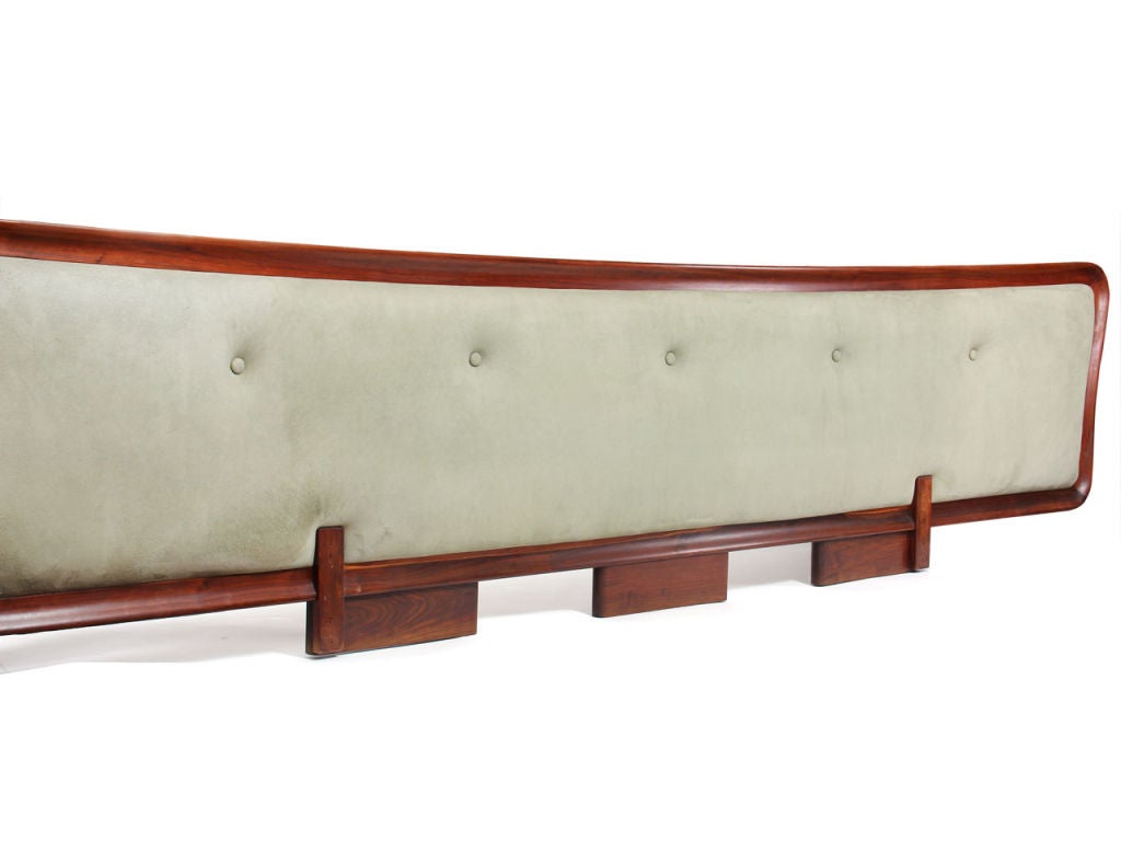 An oversized upholstered headboard with an undulating walnut frame for a king mattress.