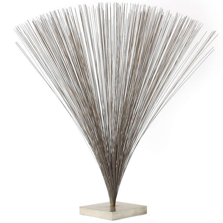 An iconic kinetic spray sculpture by Harry Bertoia fashioned from quivering steel rods anchored to a metal base.