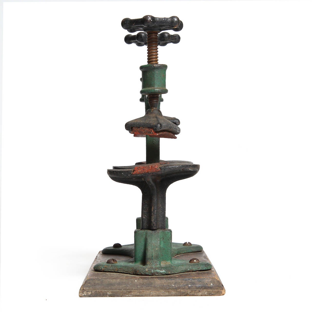 An unusual small scaled forged iron double clamp having expressive molded spade form decorations. Mounted on a stepped oak base retaining its original green polychrome.