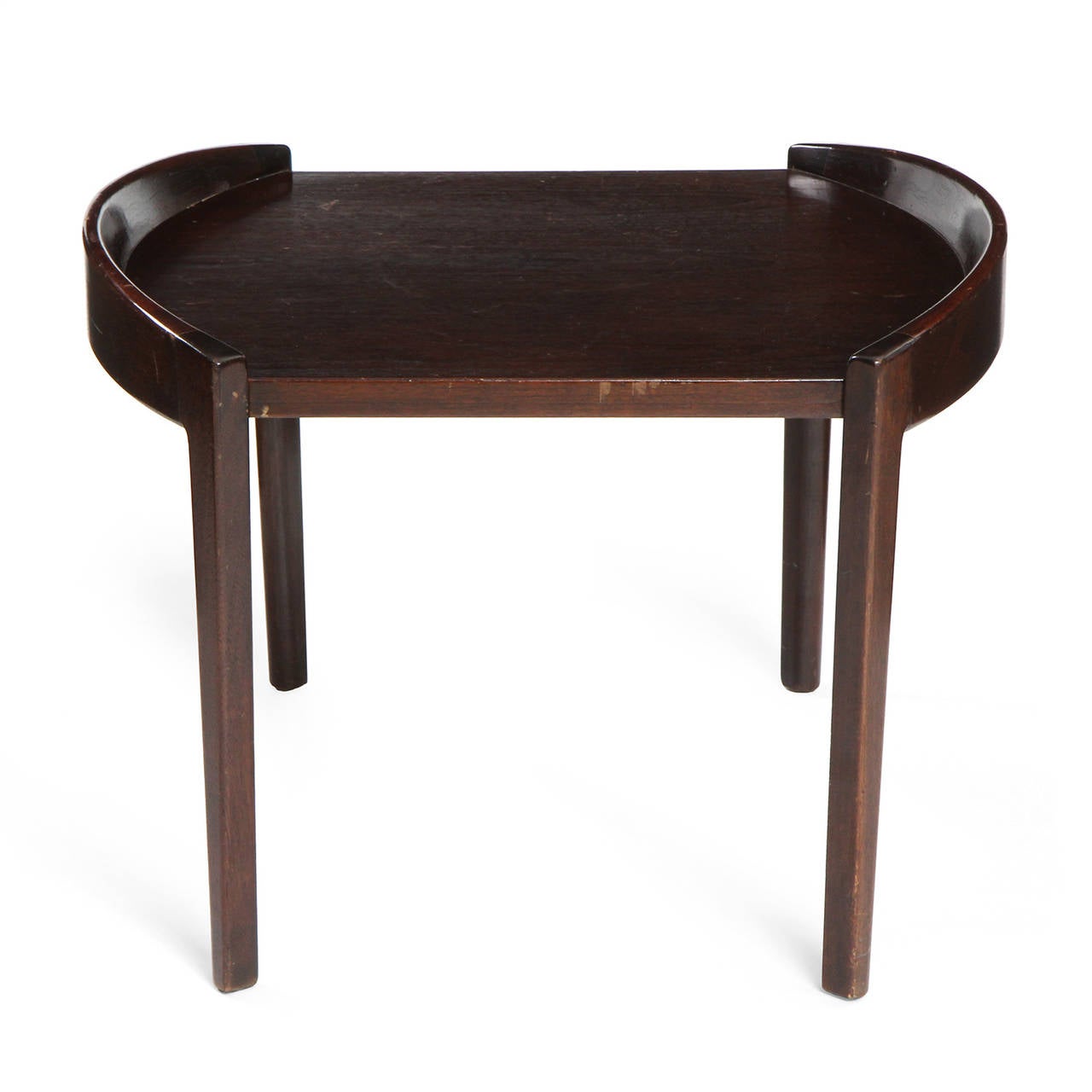 An expressive end table in rich walnut having raised and curved tapered side rails connected directly to the legs that support a floating top.