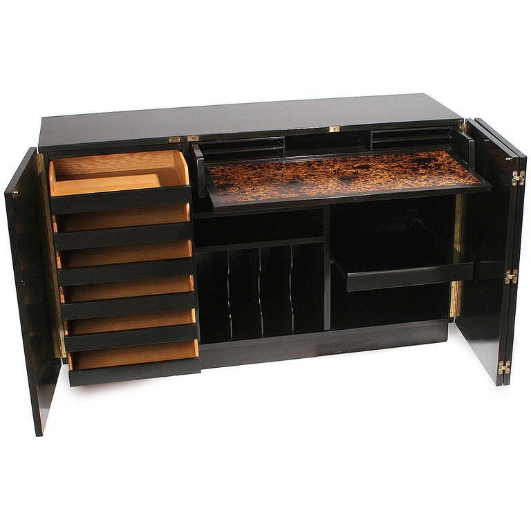 An ebonized mahogany secretary No. 6065 with pull-out writing desk and multiple drawers/shelves on a leather-wrapped plinth base, shown with superstructure, No. 6086, to serve as a bar, bookcase, or room divider.
 