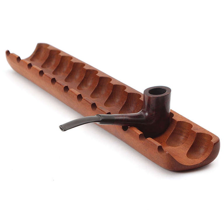 A carved and sculptural pipe rest crafted from a single piece of warm teak.