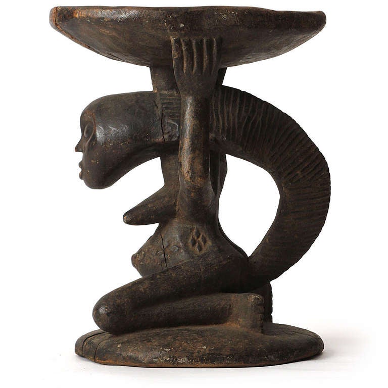 A carved anthropomorphic caryatid stool from the Congo in the form of kneeling woman holding a bowl.