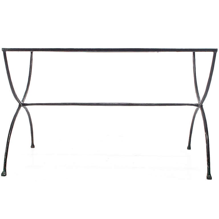 An elegantly minimalist side or occasional table in polished iron having graceful intersecting legs supporting a rectangular glass enclosed top.