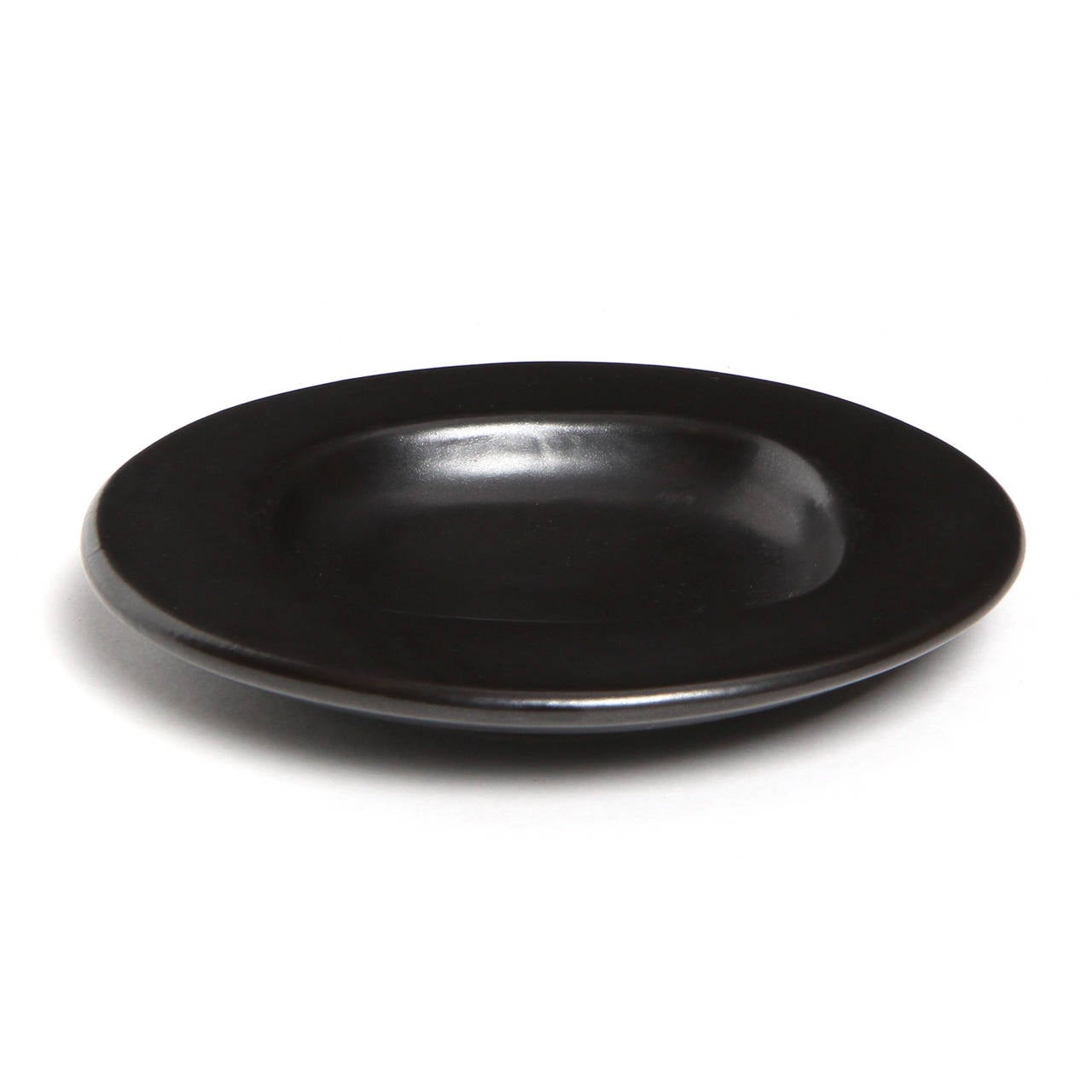 A finely rendered and substantial shallow bowl having a softened organic form and a rich and deep matte black glaze.