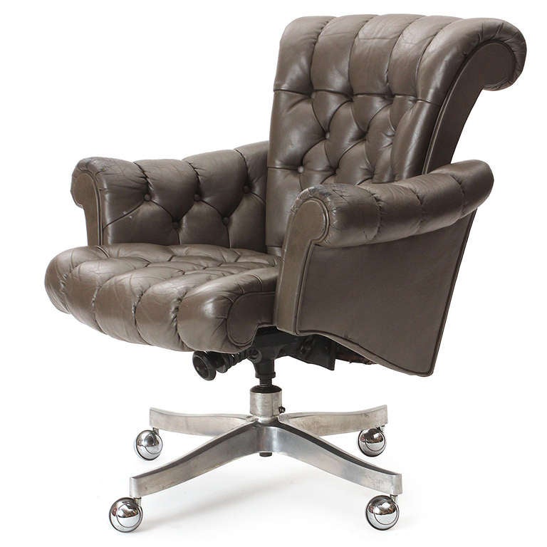 An adjustable and swiveling roll arm desk chair in the original brown leather, having a chromed four point base with casters.