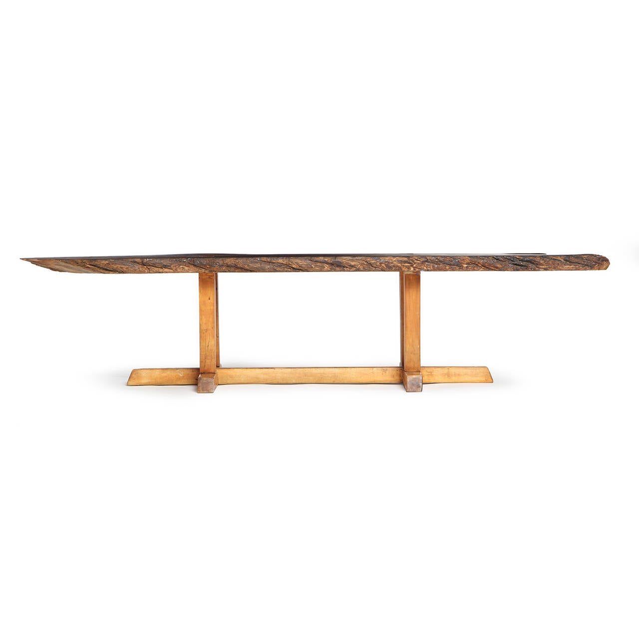 Table basse expressive et finement travaillée, avec un plateau en noyer à bords vifs flottant sur une base architecturale.
