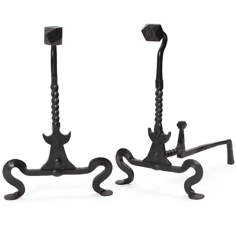 A good and expressive pair of blackened handcrafted wrought iron andirons having a scrolling and twisting structure capped by unusual faceted polyhedrons.