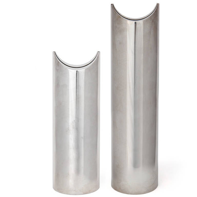 A masterfully rendered and sculptural pair of vases in chromed steel of vertical cylindrical form with expressive indented tops and slotted openings.