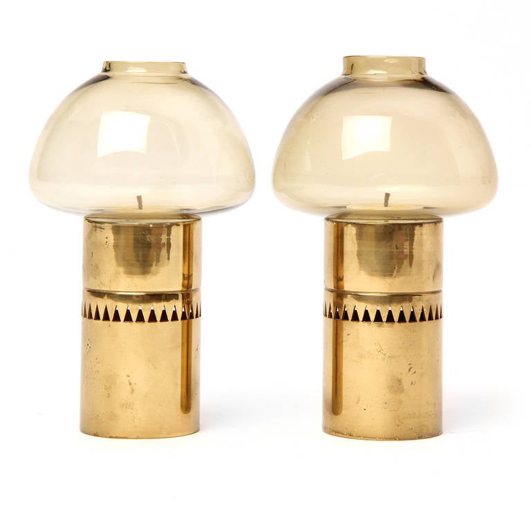 A diminutive pair of brass and blown glass hurricane candle lamps, the brass body having an expressive detail of encircling pierced triangles.