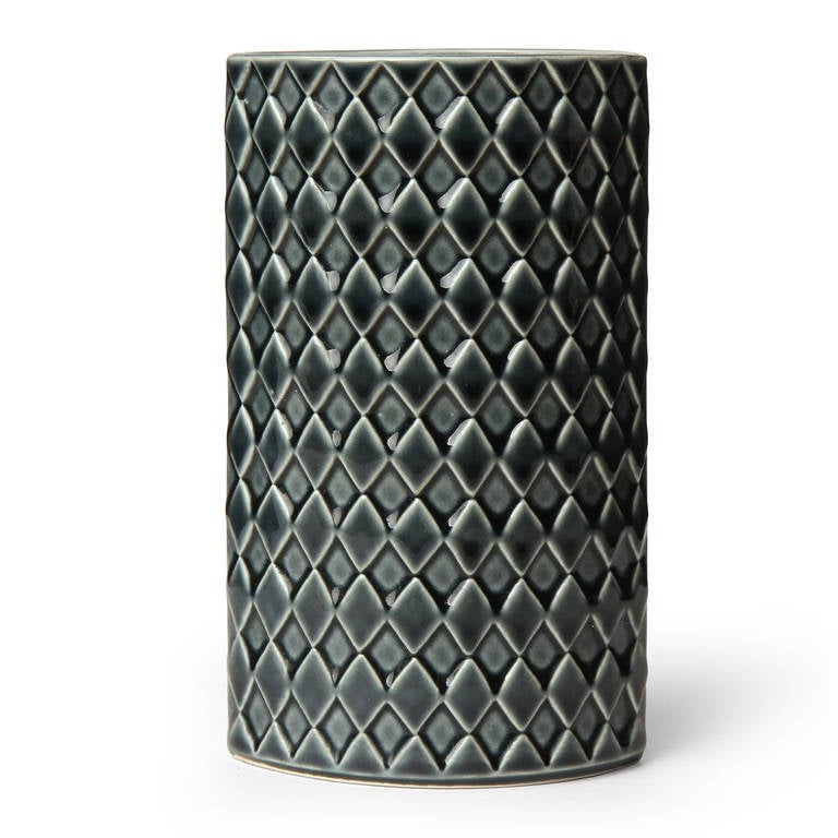 A graphic ceramic elliptical vase having a rich smoky grey-to-green glaze and an all-over embossed diamond pattern.