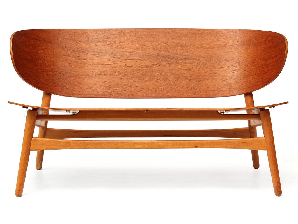 A bench with a laminated teak back and seat and a beech frame. Designed by Hans Wegner and made by Fritz Hansen