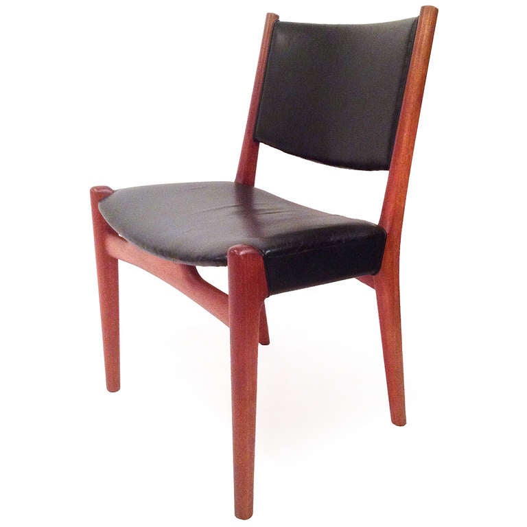 An elegant side chair with a generous exposed teak frame and a gently curved seat and back wrapped in black leather.