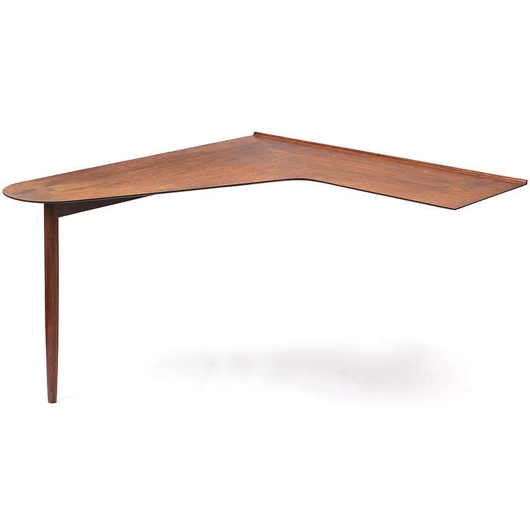 A sculptural and interesting craft-movement L-shaped wall-mounted desk made of richly grained walnut and having a single dowel leg support.