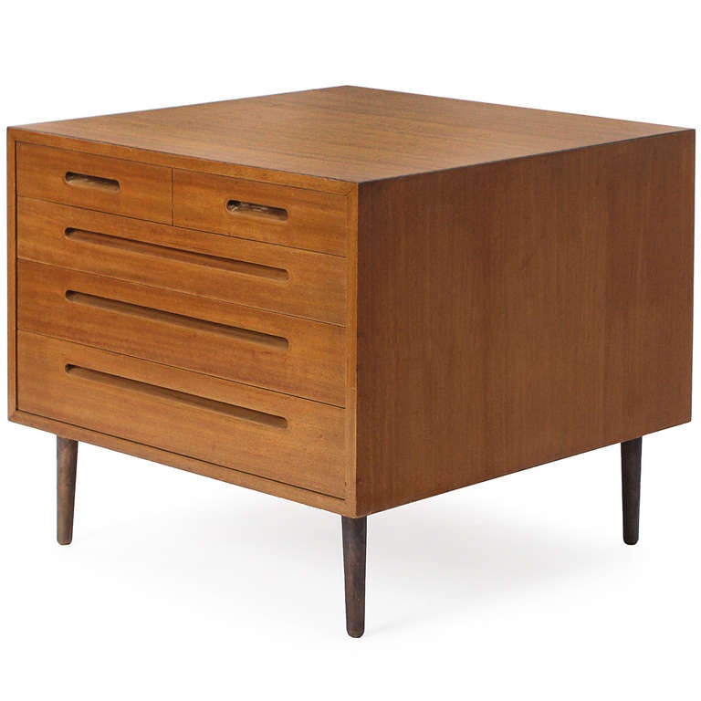 An elegantly austere and finely crafted chest of drawers in bleached walnut having a two-over-three configuration channelled recessed pulls and dowel-form legs crafted of anodized aluminum.