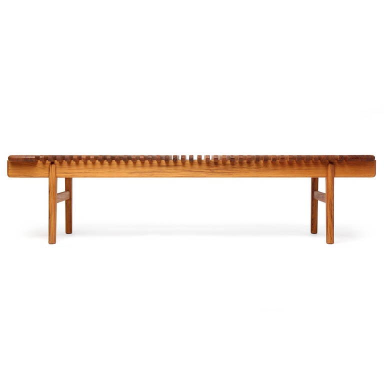 An elegant and beautifully simple bench or low table in solid teak, the top fashioned from rounded-edged slats floating on running rails. Designed by Hans Wegner, Cabinetmaker, PP Mobler.