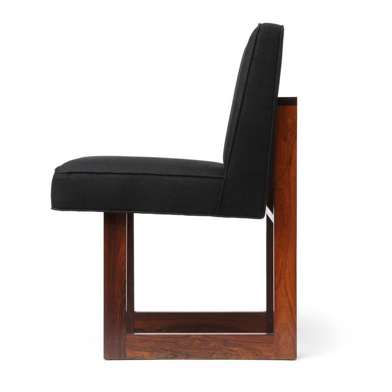 An elegant armless side chair having an L-shaped upholstered seat supported by an architectural and rectilinear exposed rosewood frame with sled legs.
