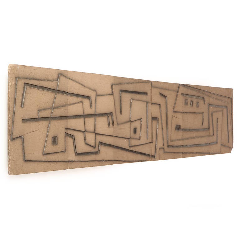 A large scaled and masterfully rendered earth toned sculptural horizontal plaque made of a ceramic composition, having a bold incised abstract and geometric design and cleated for easy hanging.