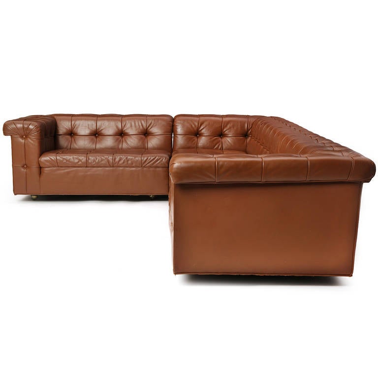 A rare, generously proportioned and highly comfortable L-shaped sectional sofa on casters having rich tuck-and-roll button-tufted caramel-colored leather upholstery.