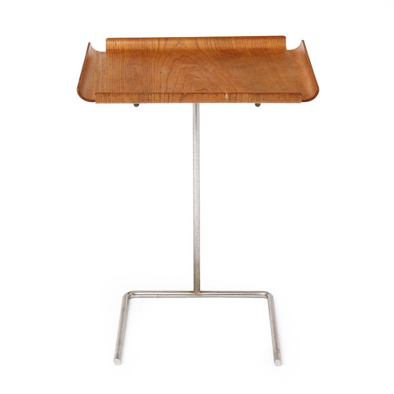 An architectural and minimalist tray table having an expressive molded walnut tray floating in a spare and adjustable matte steel stand.