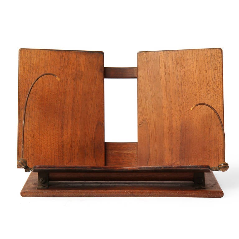 A superb, impeccably crafted and detailed book holder in warmly patinated teak having a pivoting curved back rest and distinctive pivoting curved metal page holders.