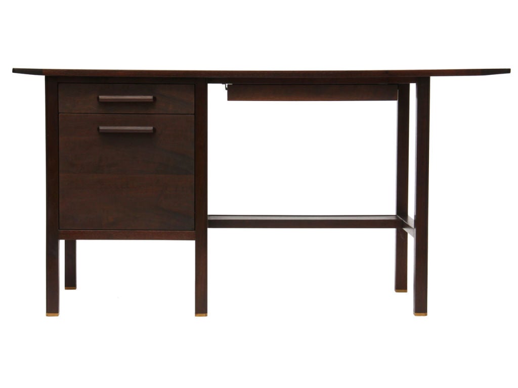 A desk with a bowed trapezoidal walnut top over an ebonized mahogany base with file drawer and lower shelf. Barrel back desk chair (also by Dunbar) is available in a separate listing - U1101248903457.