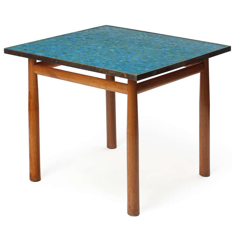 An uncommon and fine square occasional table in pale mahogany having round dowel legs and a top of pale blue and green Italian glass mosaic tile bounded by a warm brass perimeter band.