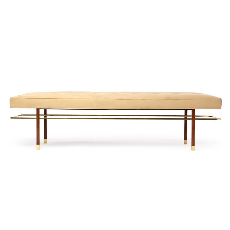 An elegant and beautifully detailed button-tufted upholstered bench having a spare rectilinear form, square rosewood legs with brass sabots and a distinctive floating lap-jointed brass stretcher.