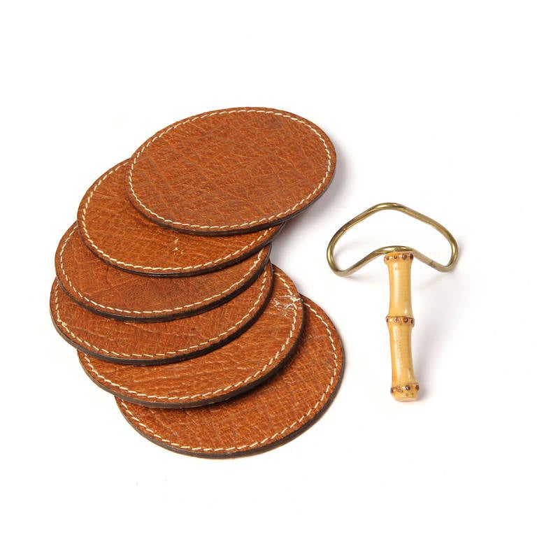 An impeccably crafted set of six hand-stitched leather coasters housed in their original bamboo and brass stand.