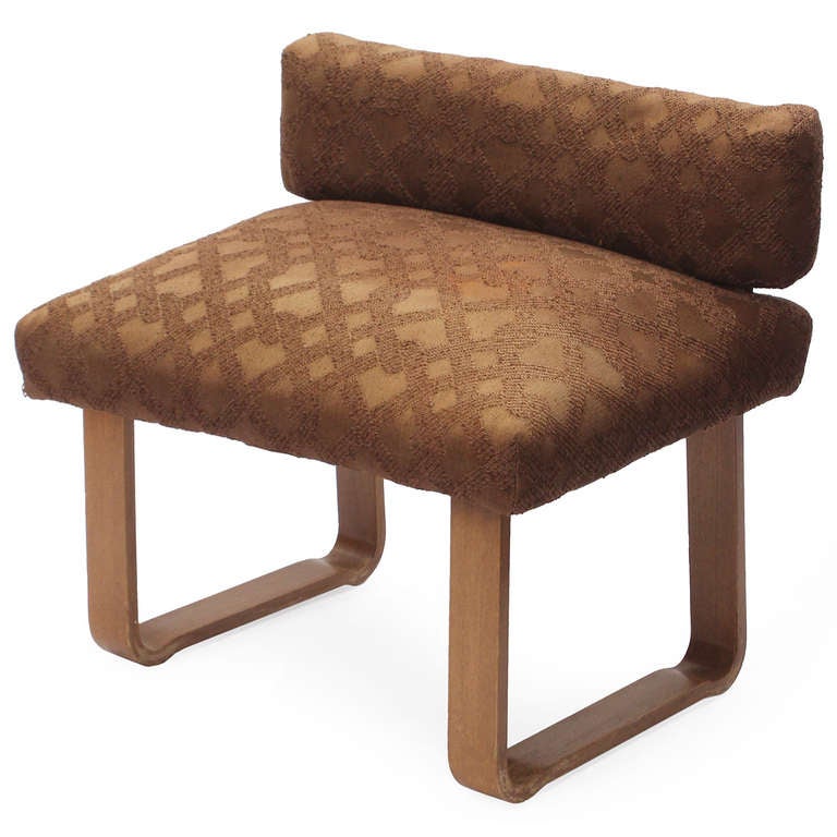 A small and useful bench having continuous laminated walnut 'sled' legs and earth-toned grid-patterned wool upholstery.