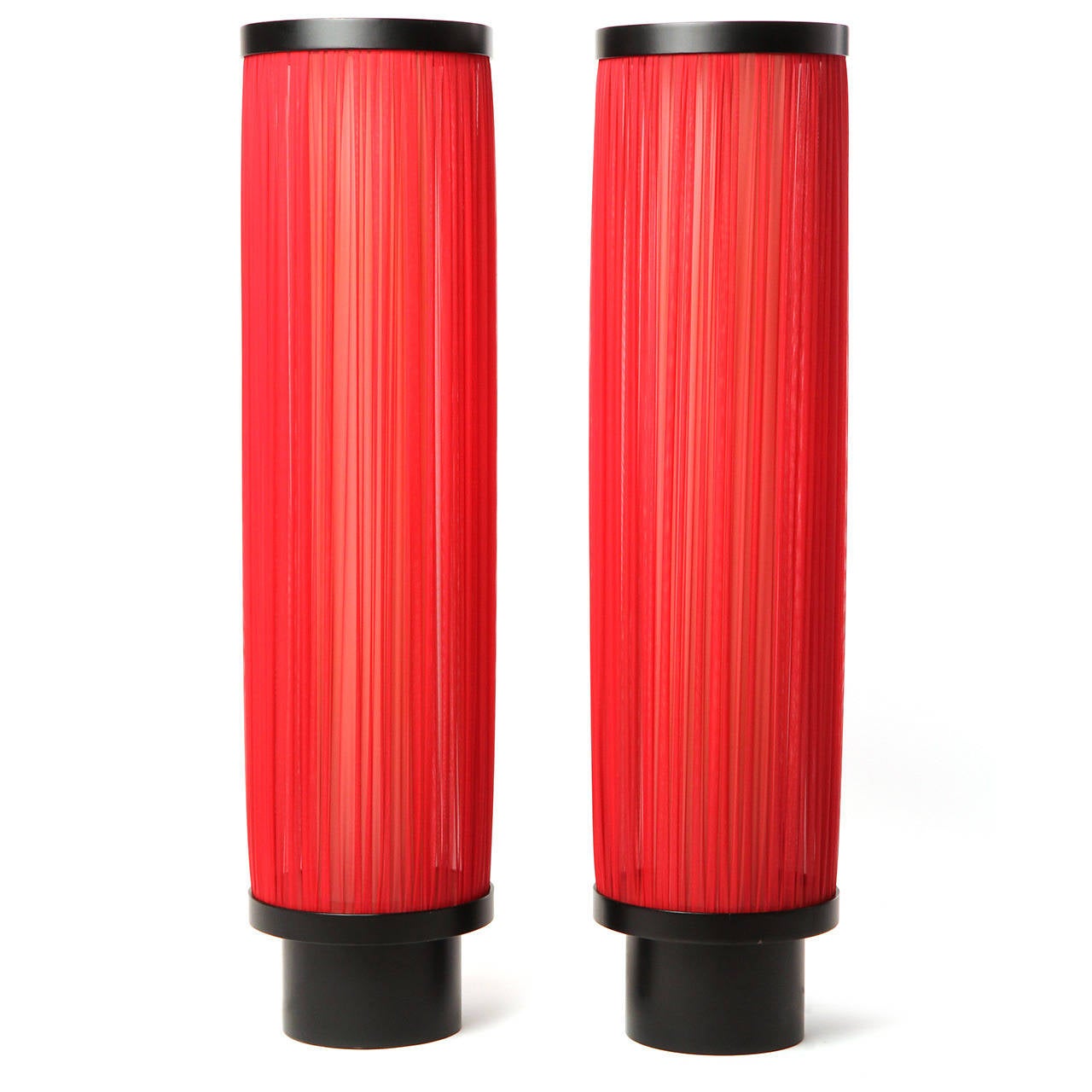 An unusual and highly expressive pair of tall columnar floor lamps having lacquered wooden bases supporting perspex tubes encircled by translucent swaths of crimson fabric.